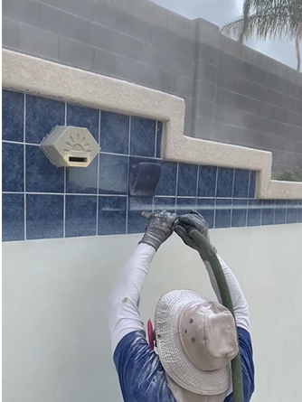Person fixing or installing a pool water outlet on tiled pool wall.